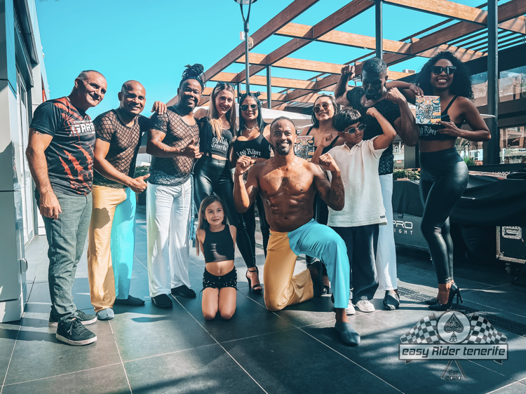 A group of people are posing for a picture in front of a car.