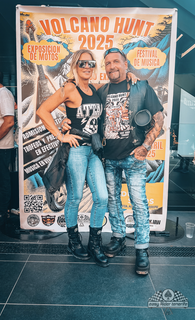 A man and a woman are posing for a picture in front of a volcano hunt poster.