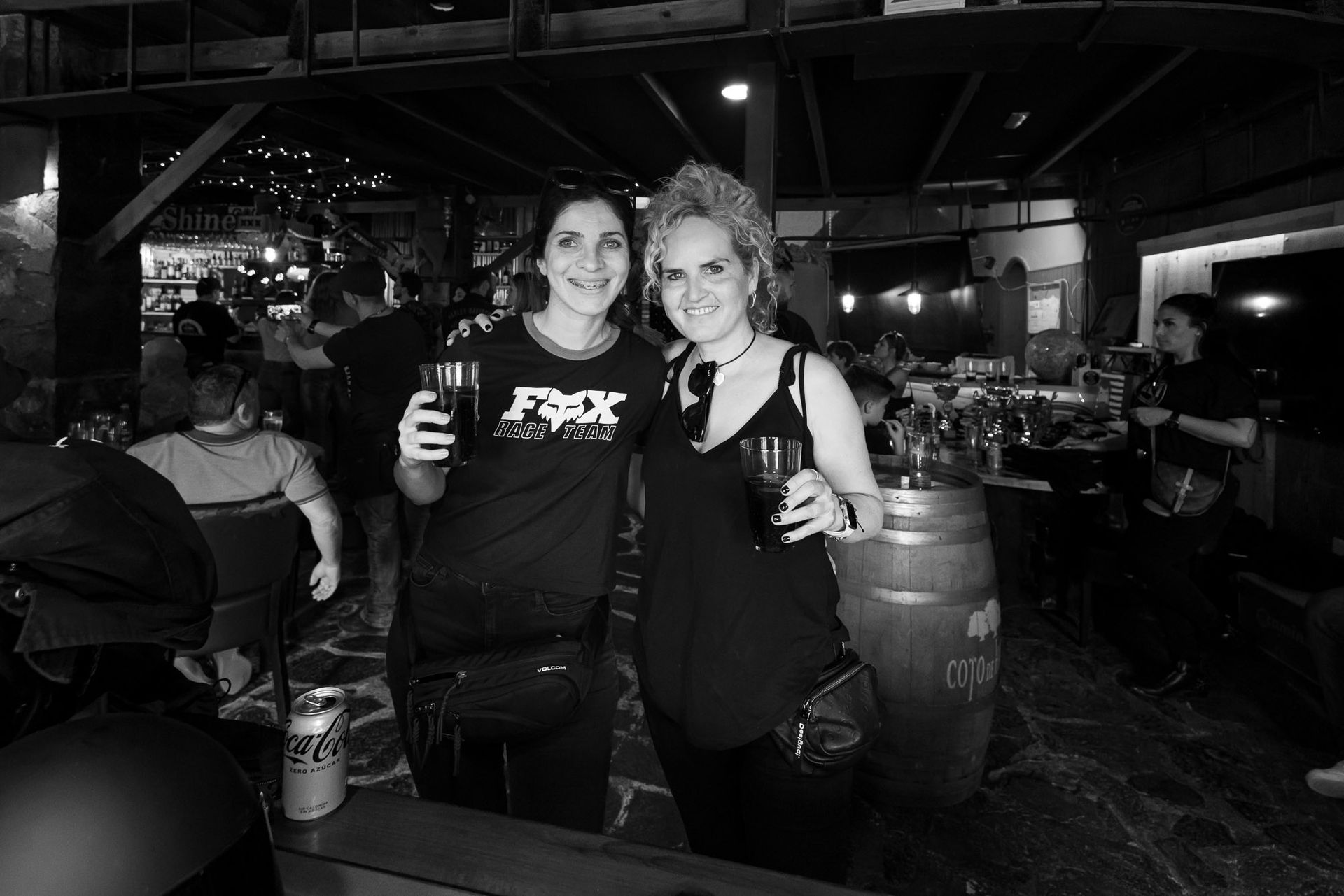 Two women are posing for a picture in a bar and one of them is wearing a shirt that says fox