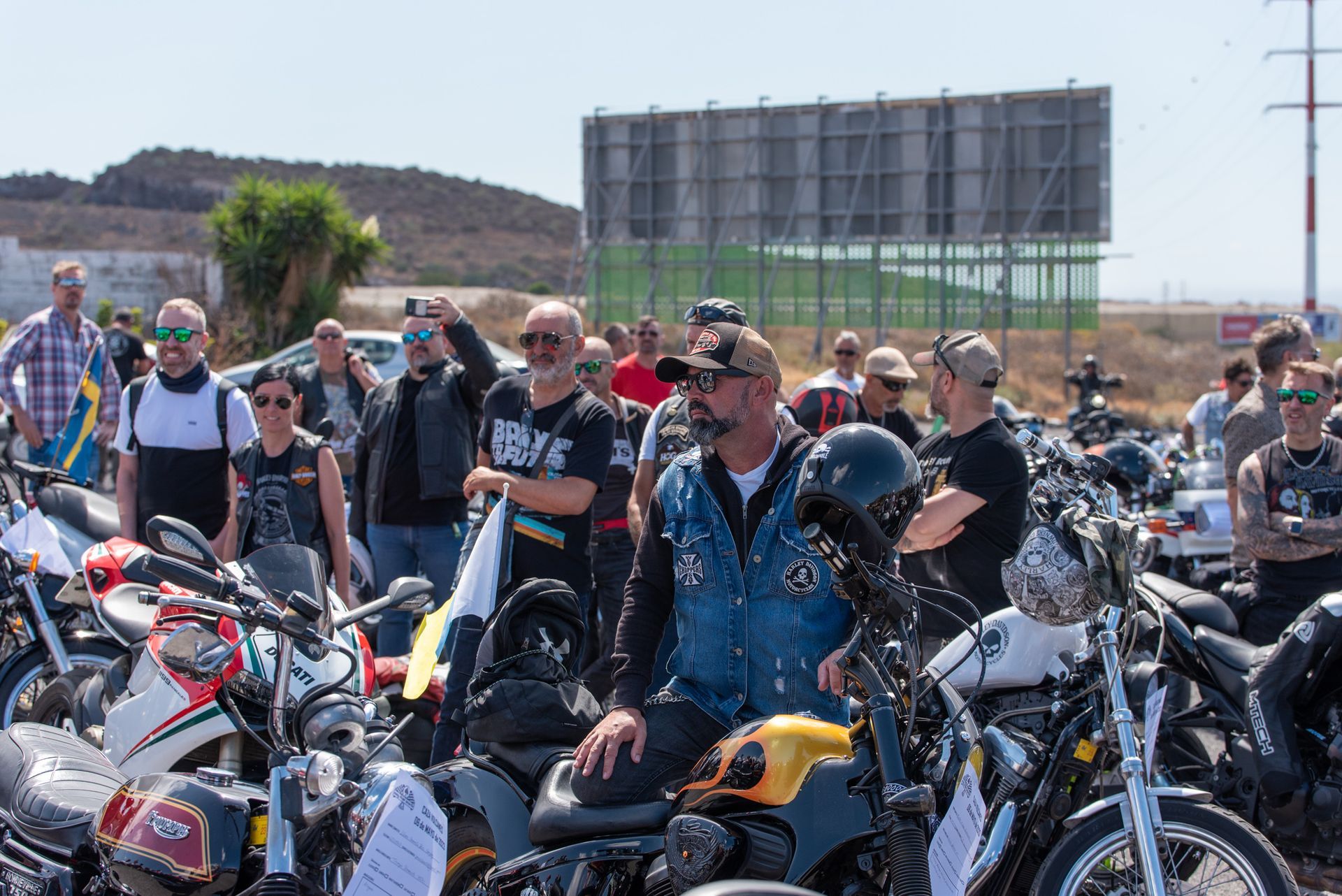 A group of people are sitting on motorcycles in a parking lot.
