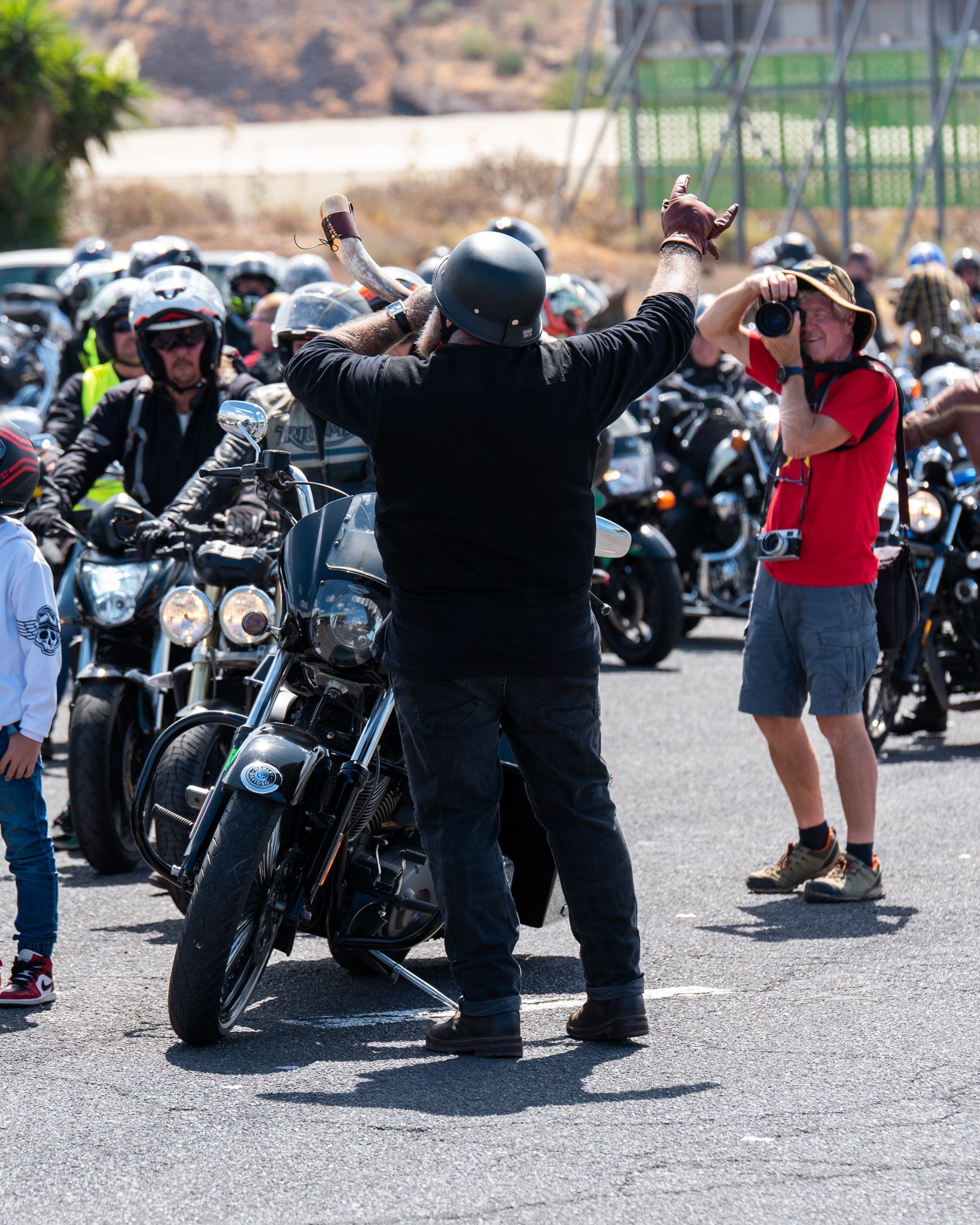A man in a red shirt is taking a picture of a group of motorcycle riders