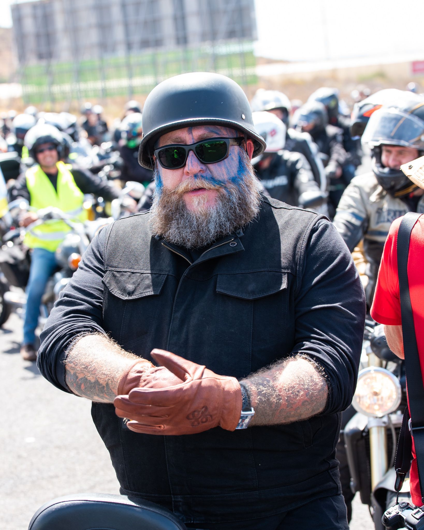 A man with a beard wearing a helmet and sunglasses is riding a motorcycle
