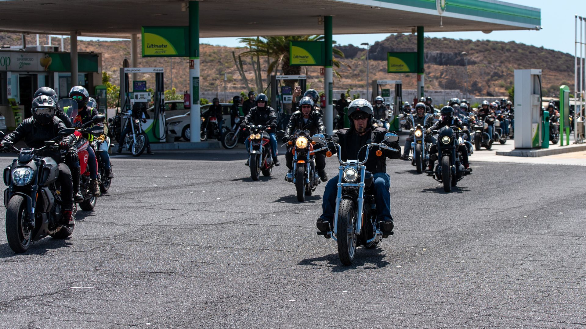 A group of people riding motorcycles in front of a gas station