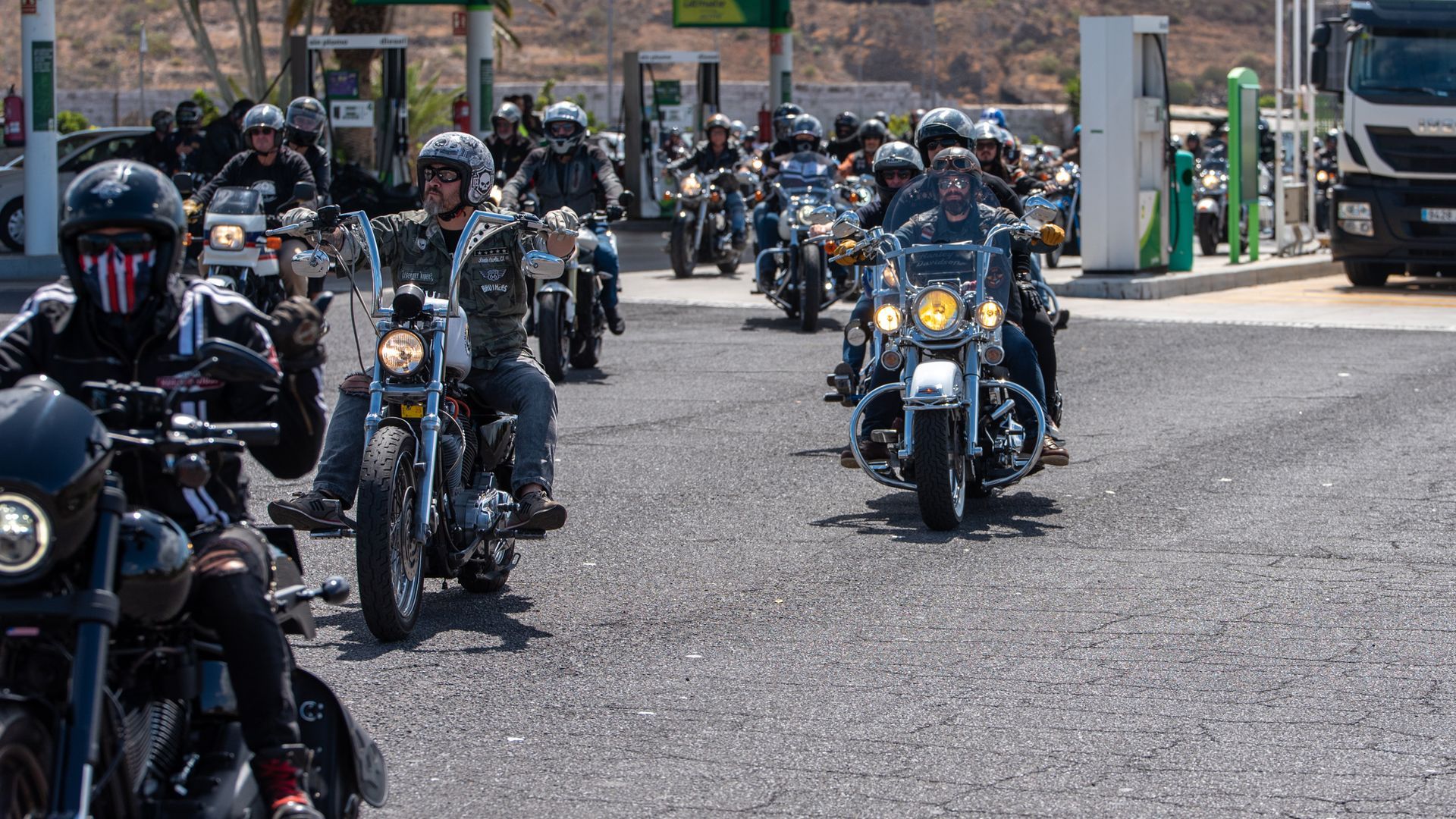 A group of motorcycle riders are riding down a road