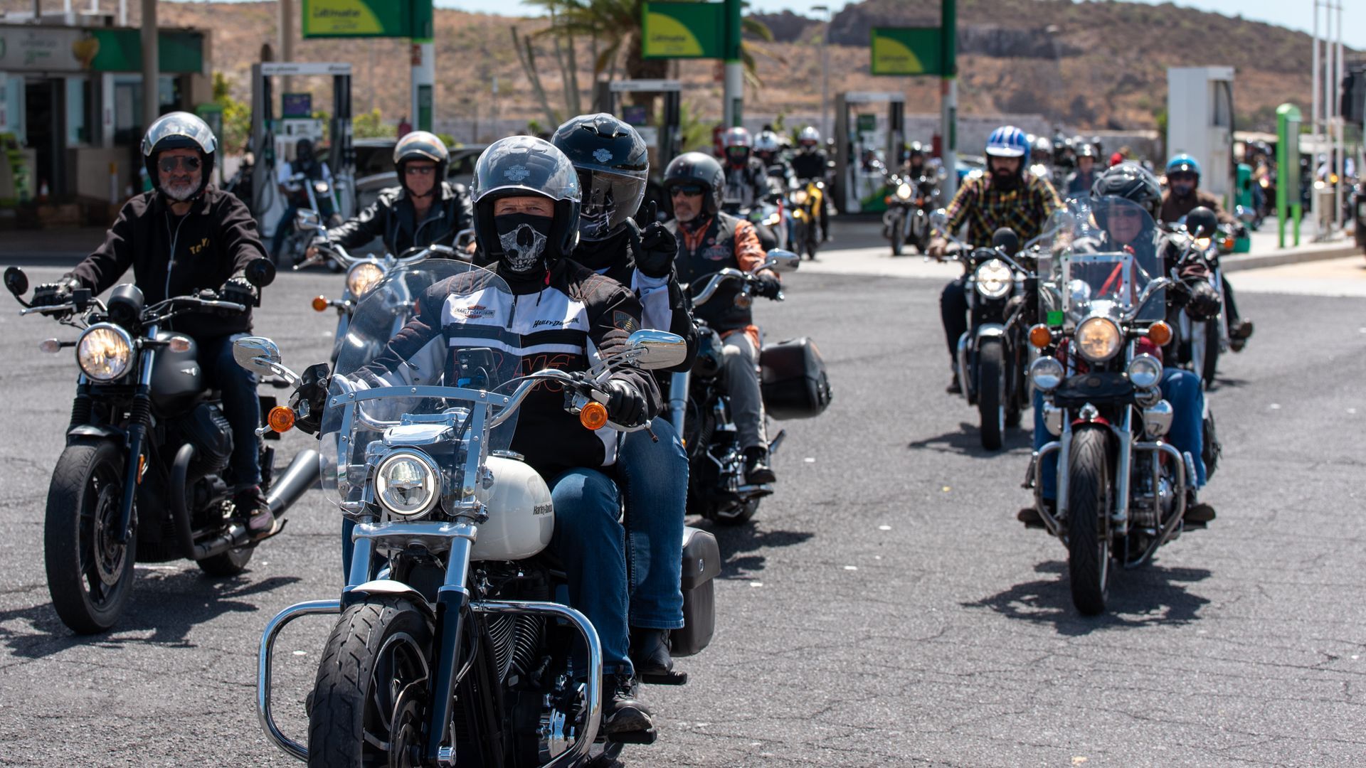 A group of people are riding motorcycles down a street