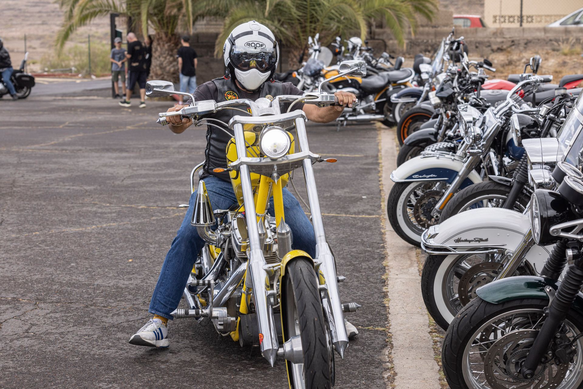 A man is riding a yellow motorcycle in a parking lot.