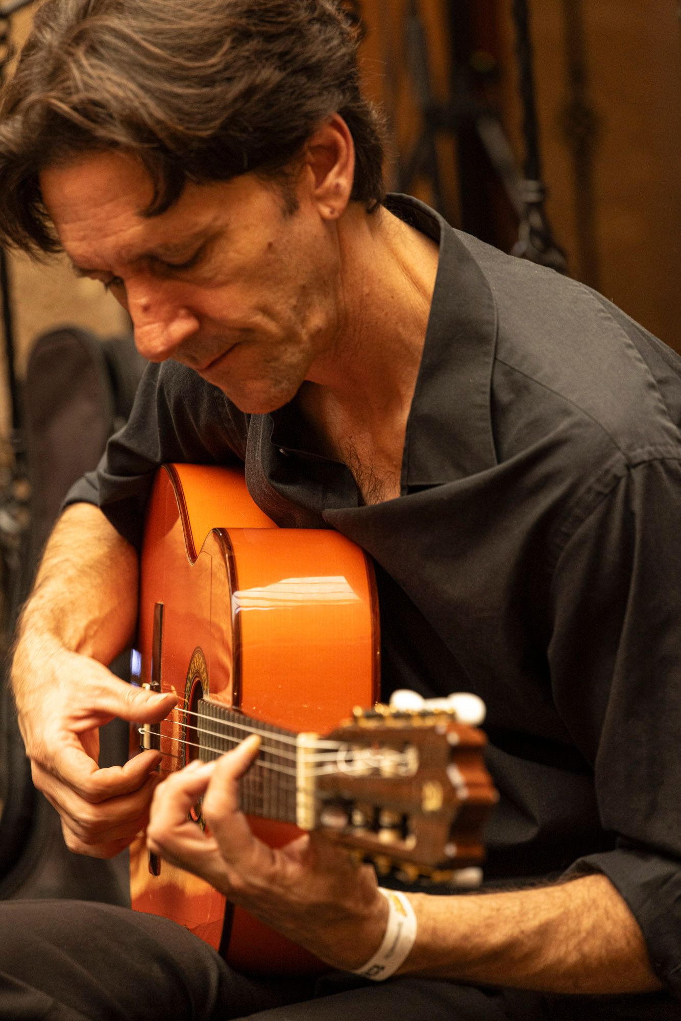A man in a black shirt is playing an orange guitar