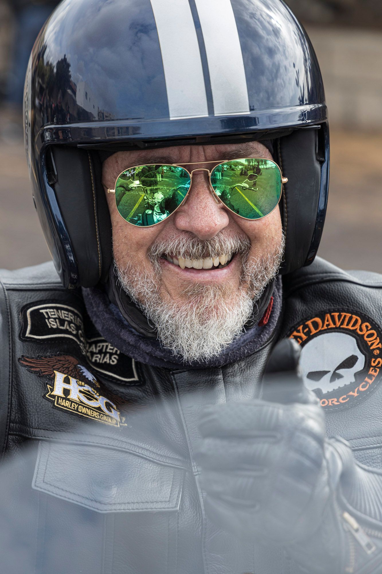 A man wearing a helmet and sunglasses is smiling.