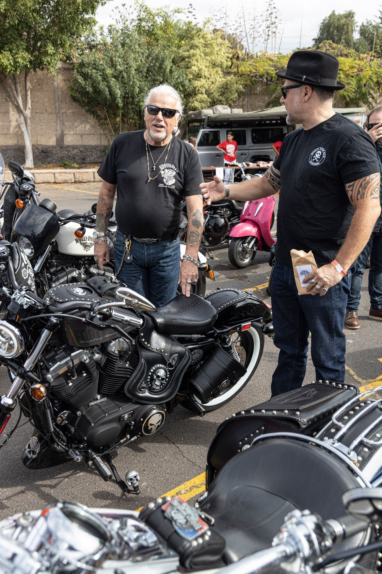 Two men are standing next to a motorcycle in a parking lot.