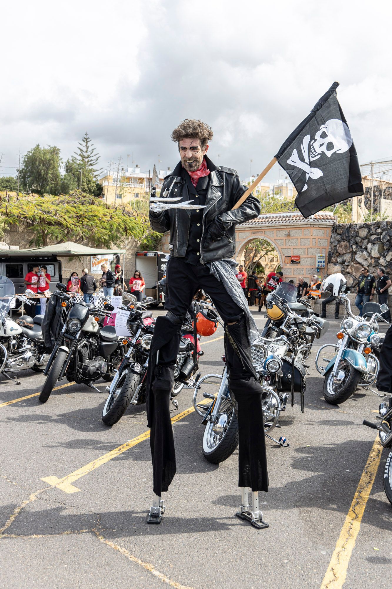 A man is standing on stilts holding a flag.