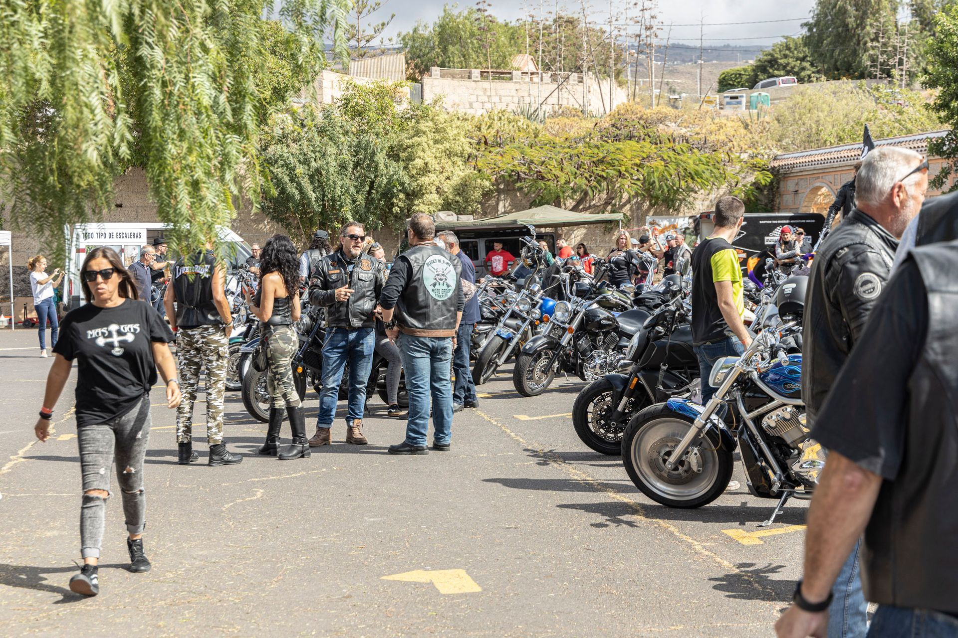 A group of people are standing in a parking lot next to motorcycles.