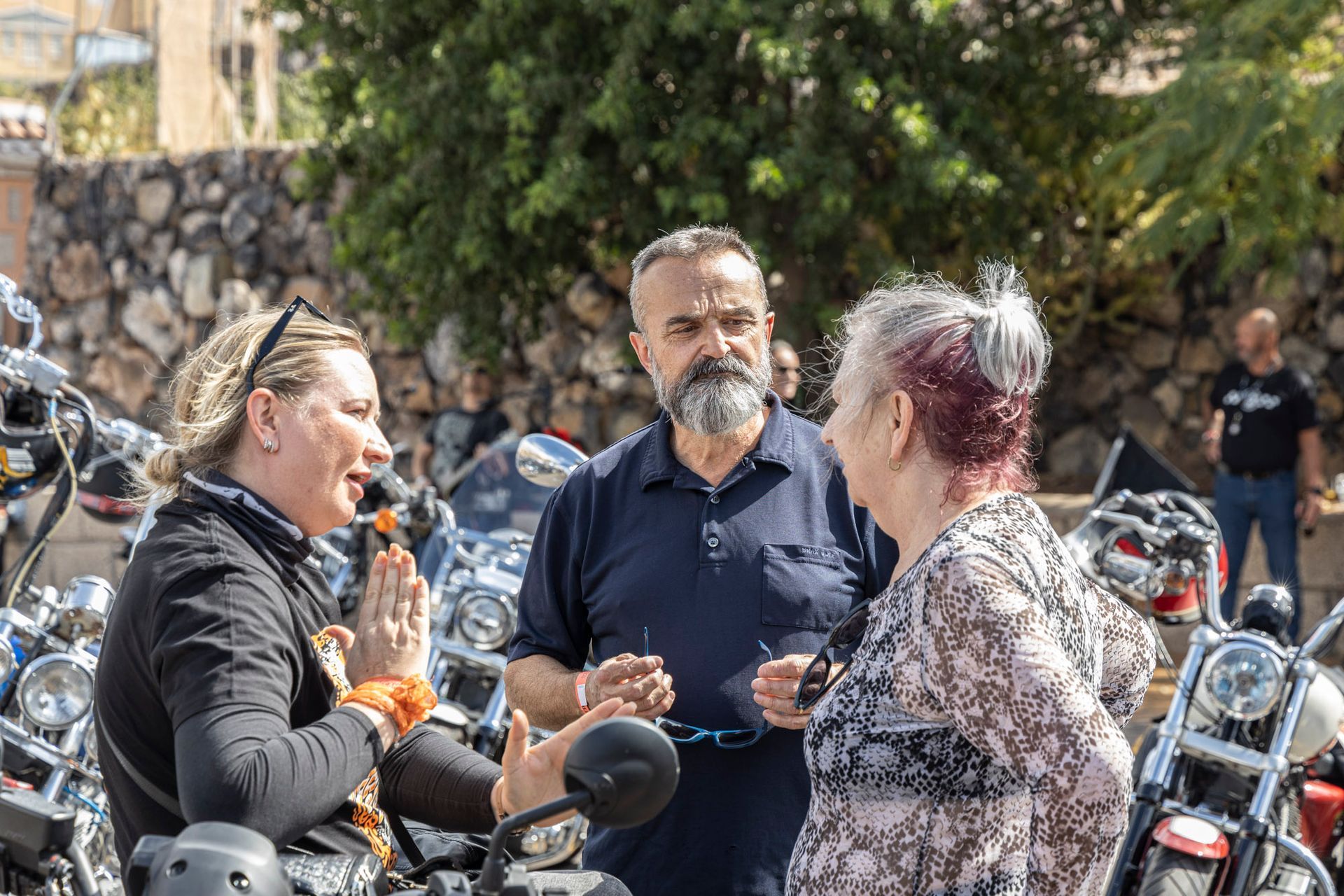 A group of people are standing next to motorcycles and talking to each other.