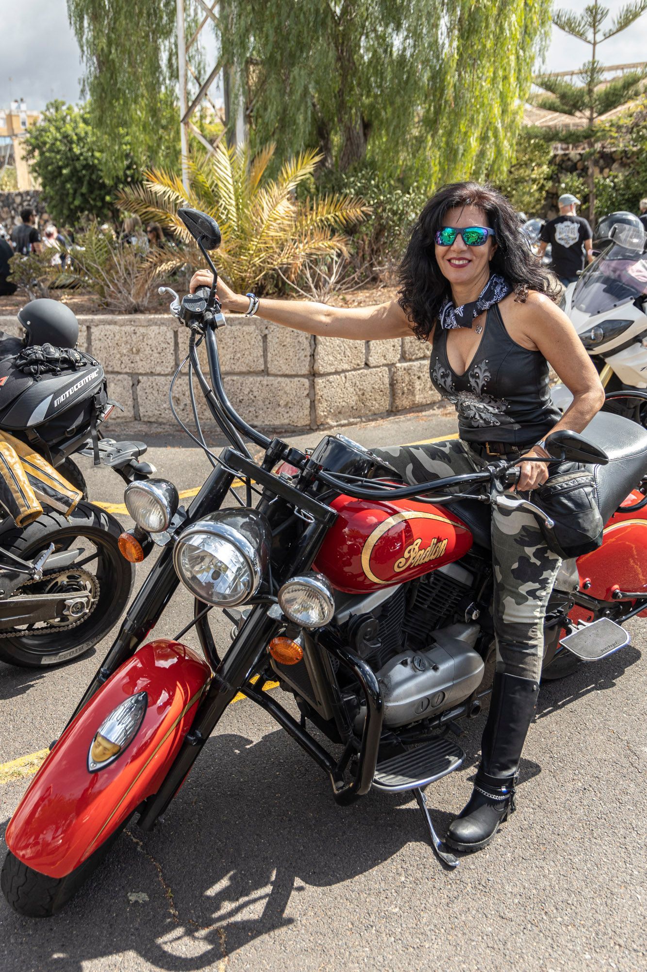 A woman is standing next to a red motorcycle.