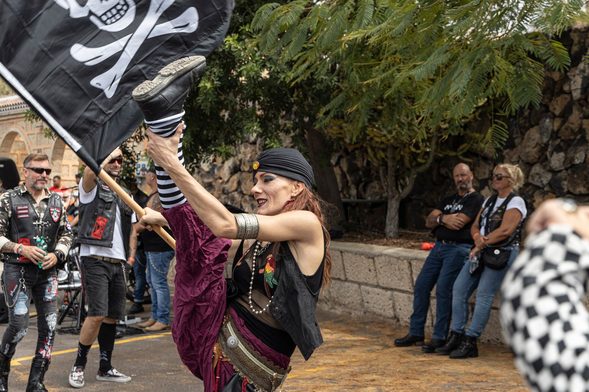 A woman in a pirate costume is holding a pirate flag.