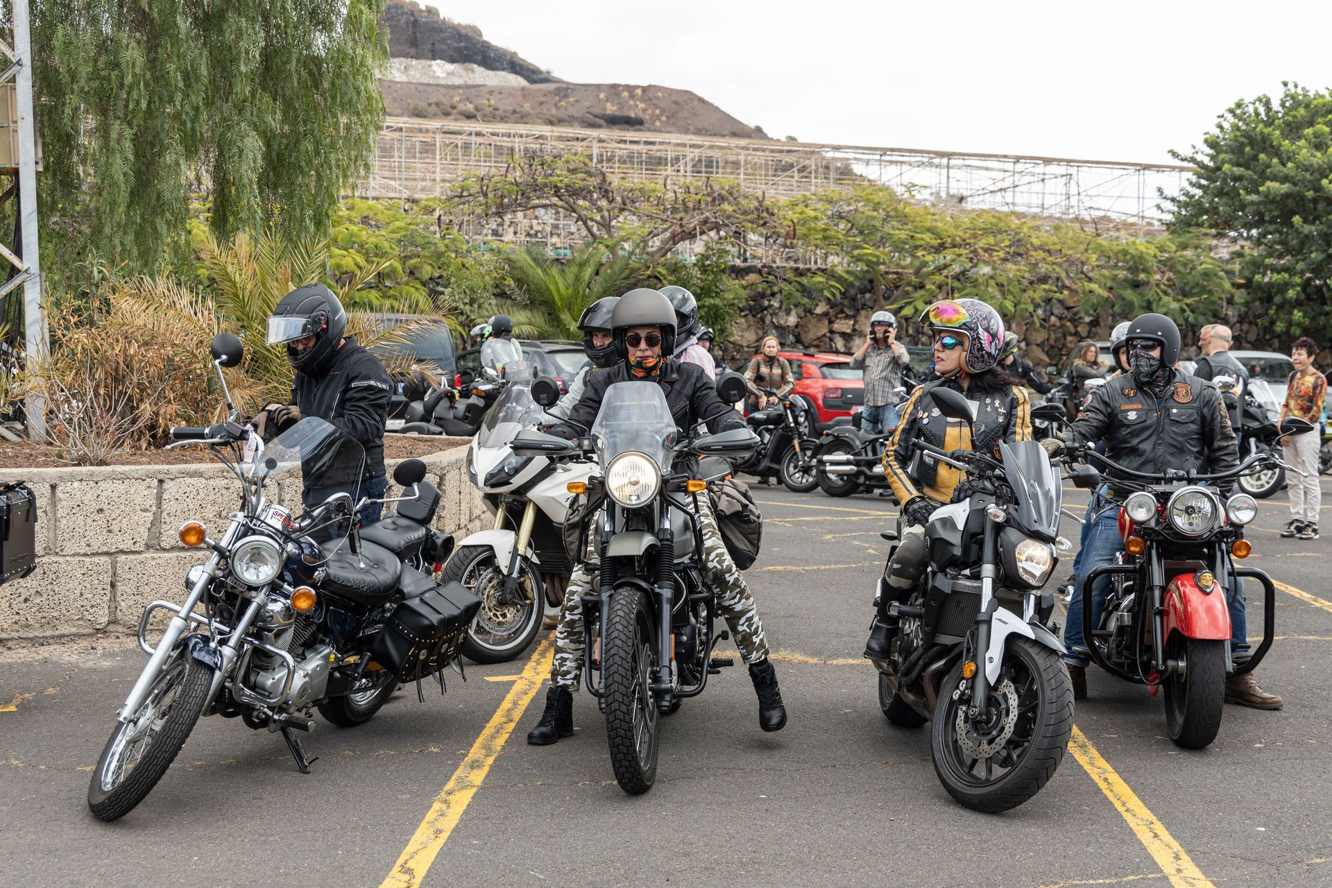 A group of people are riding motorcycles in a parking lot.