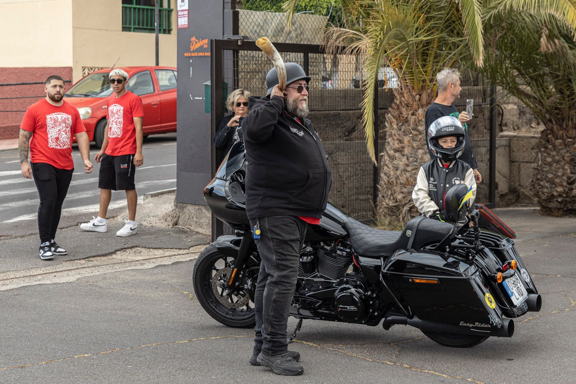 A man is standing next to a black harley davidson motorcycle.