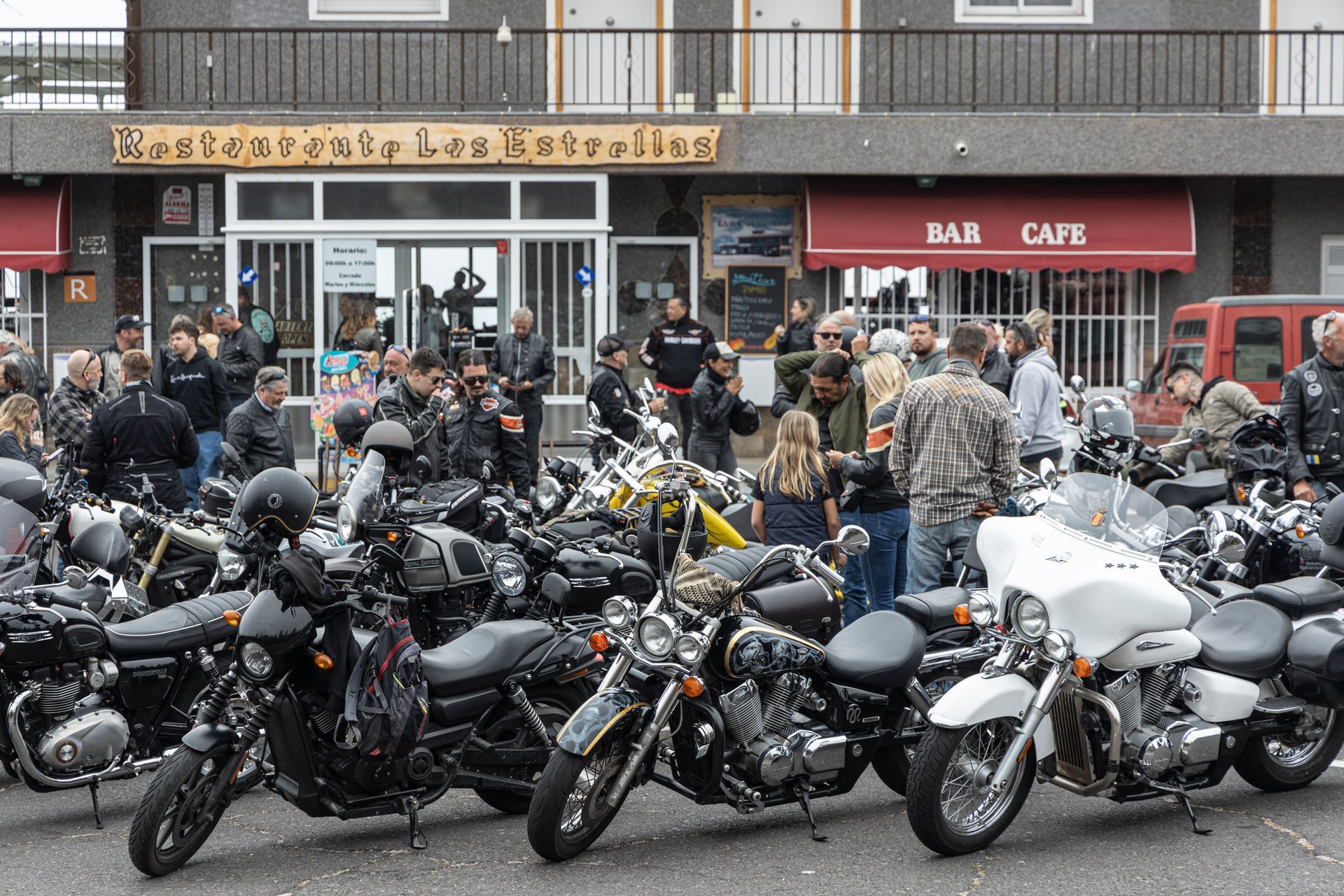 A group of motorcycles are parked in front of a building that says bar cafe