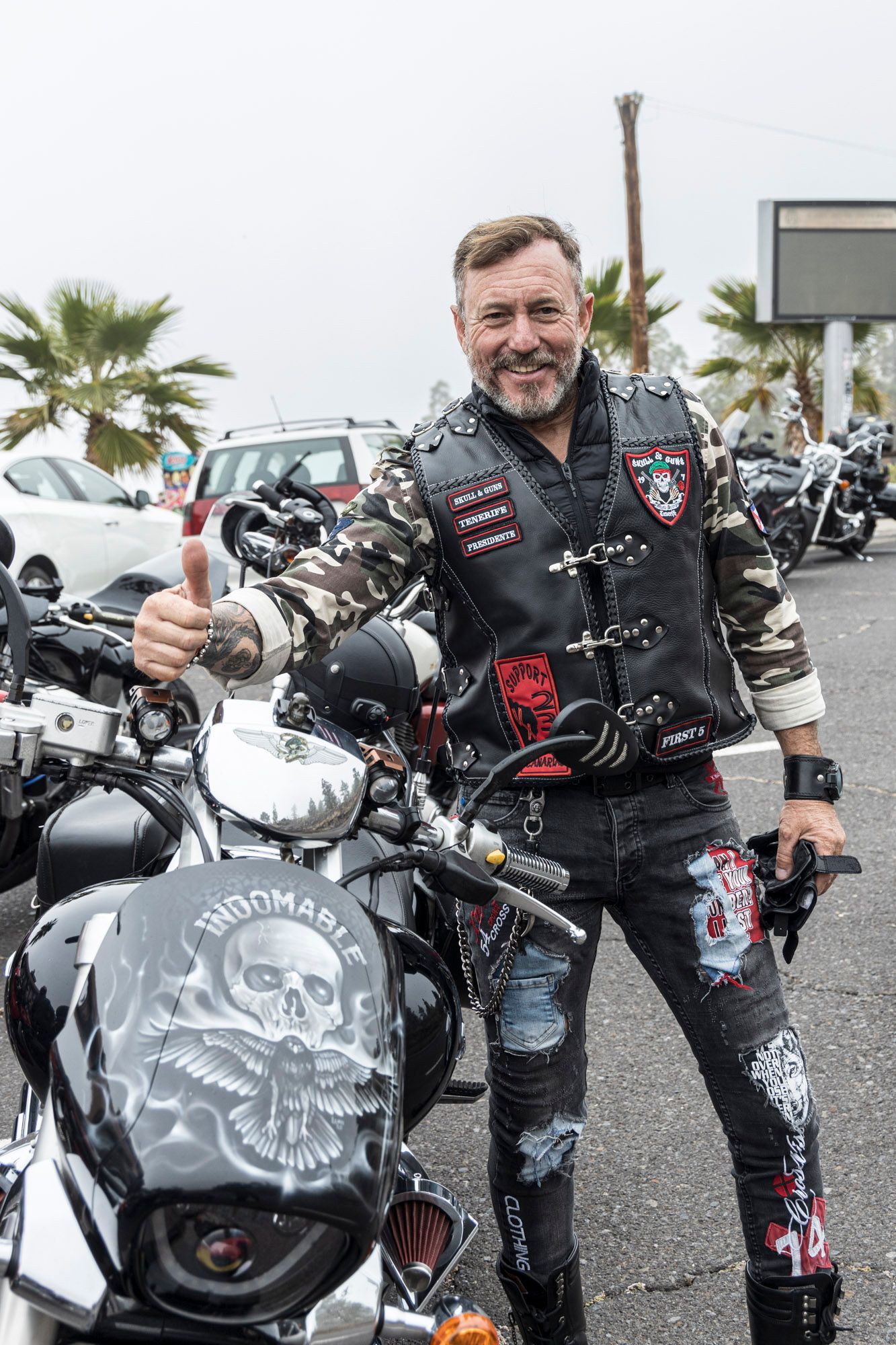 A man is standing next to a motorcycle and giving a thumbs up.