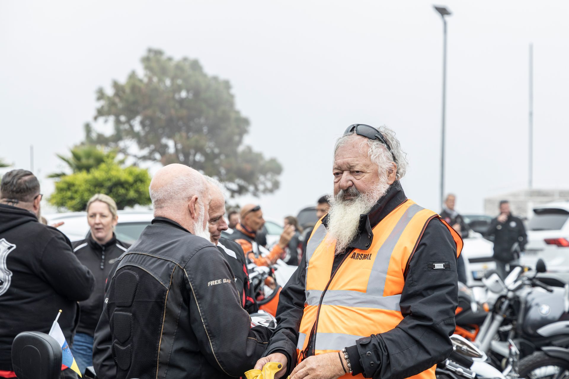 A group of men are shaking hands in a parking lot.