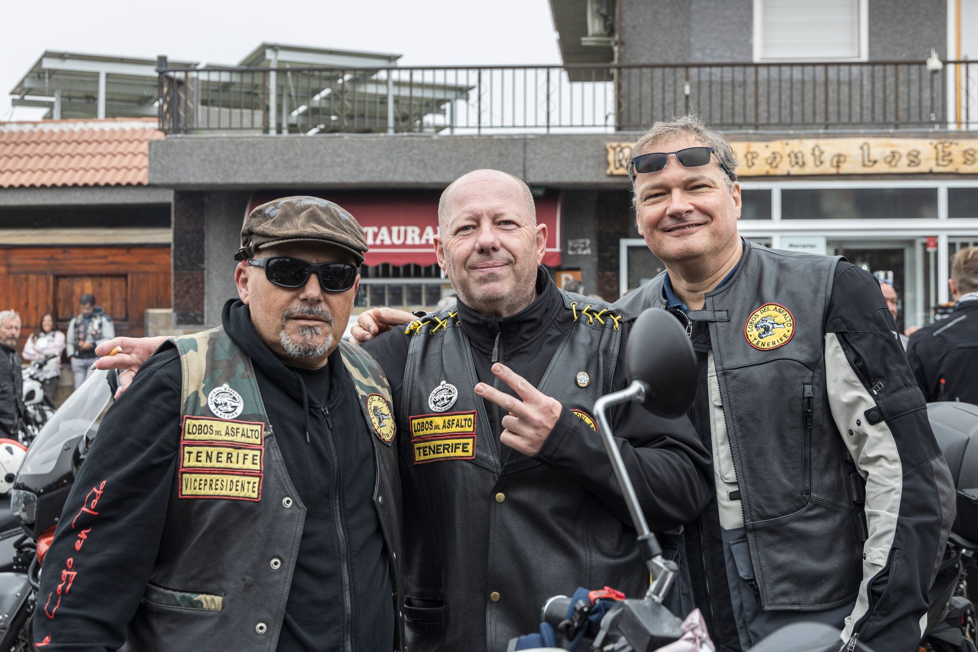 Three men are posing for a picture in front of a building.