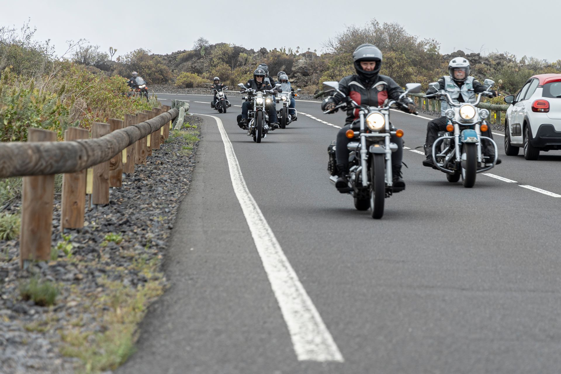 A group of people riding motorcycles down a road