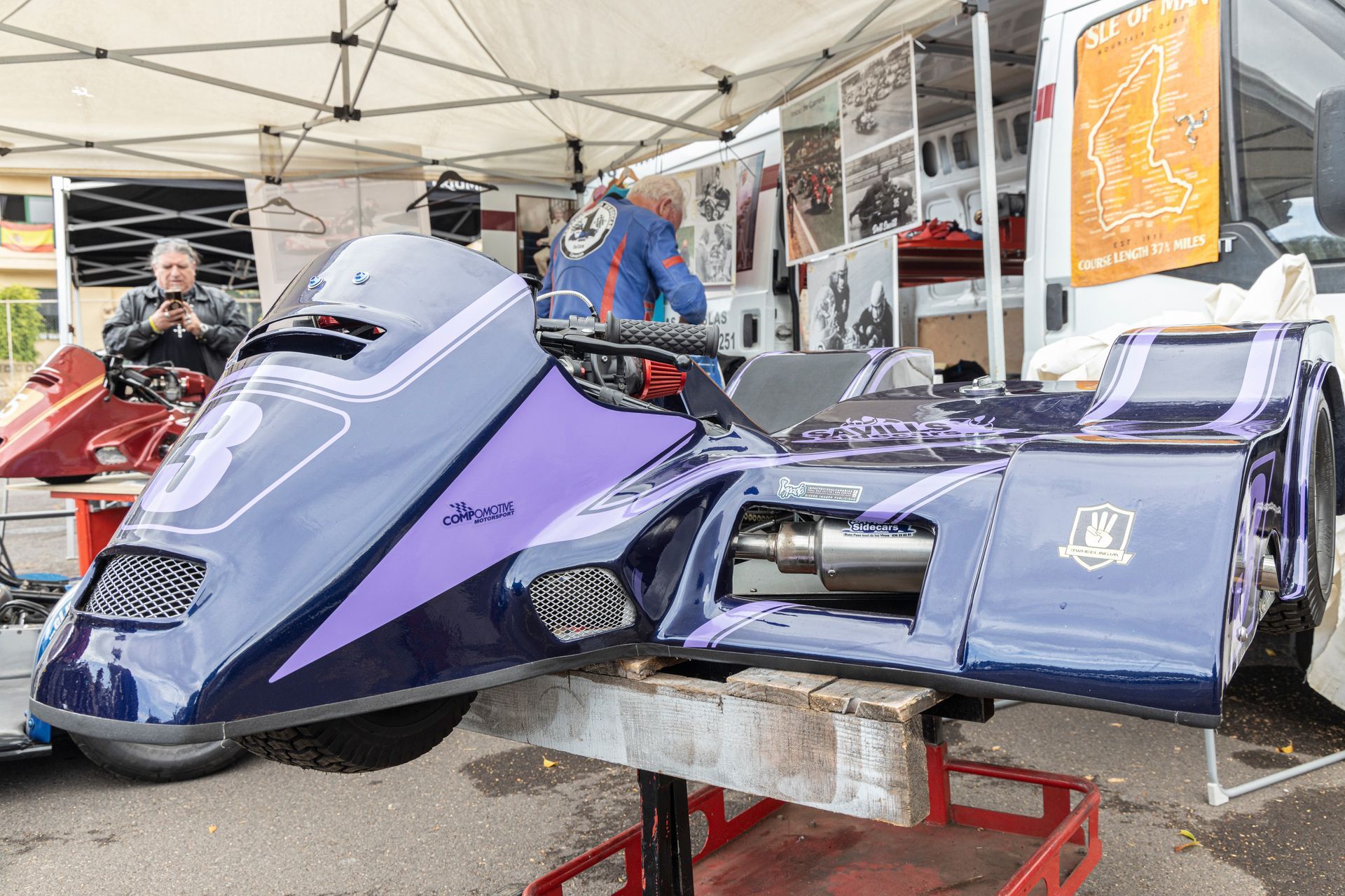 A purple motorcycle is sitting on a table in front of a tent.
