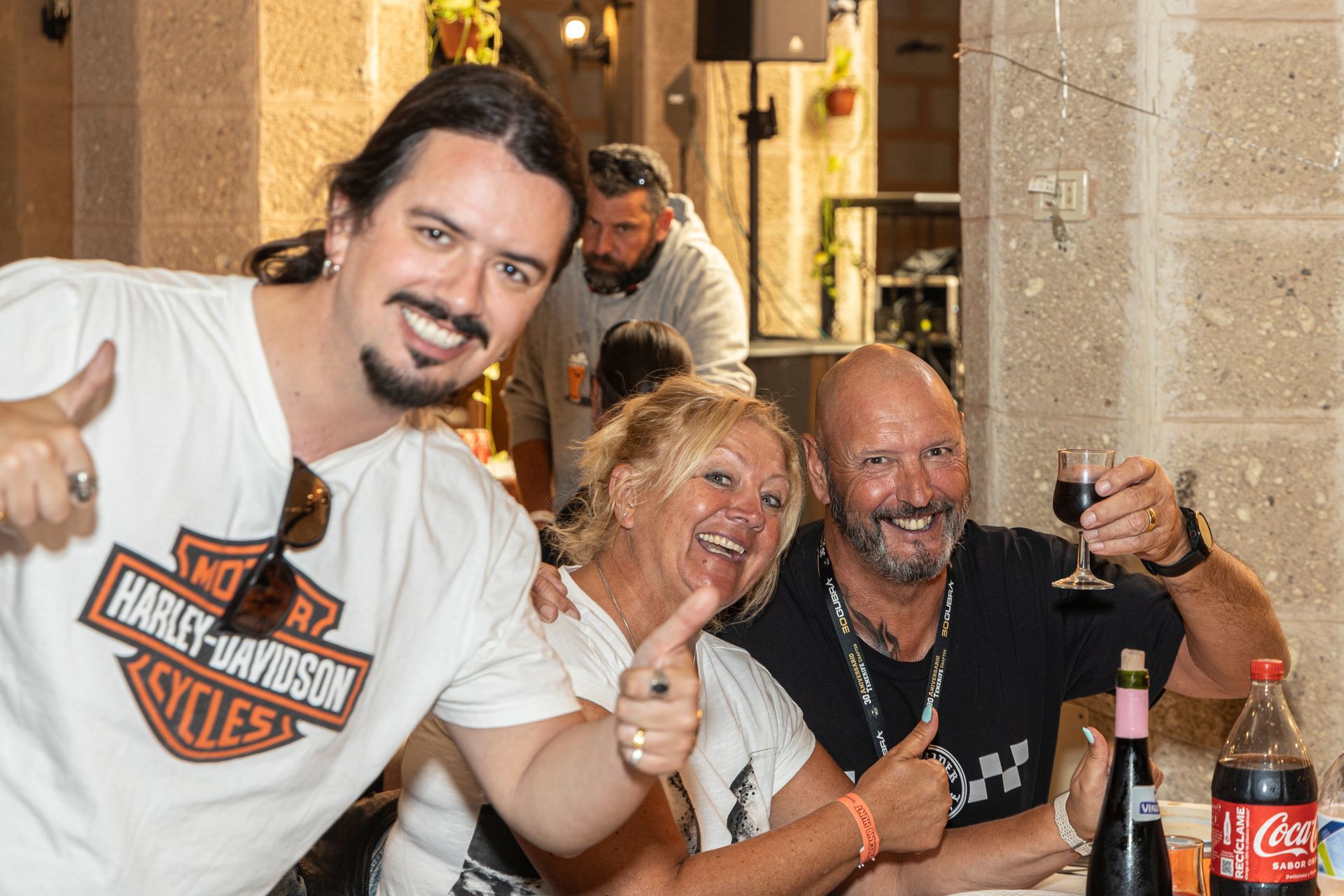 A group of people are posing for a picture and one of them is wearing a harley davidson shirt.