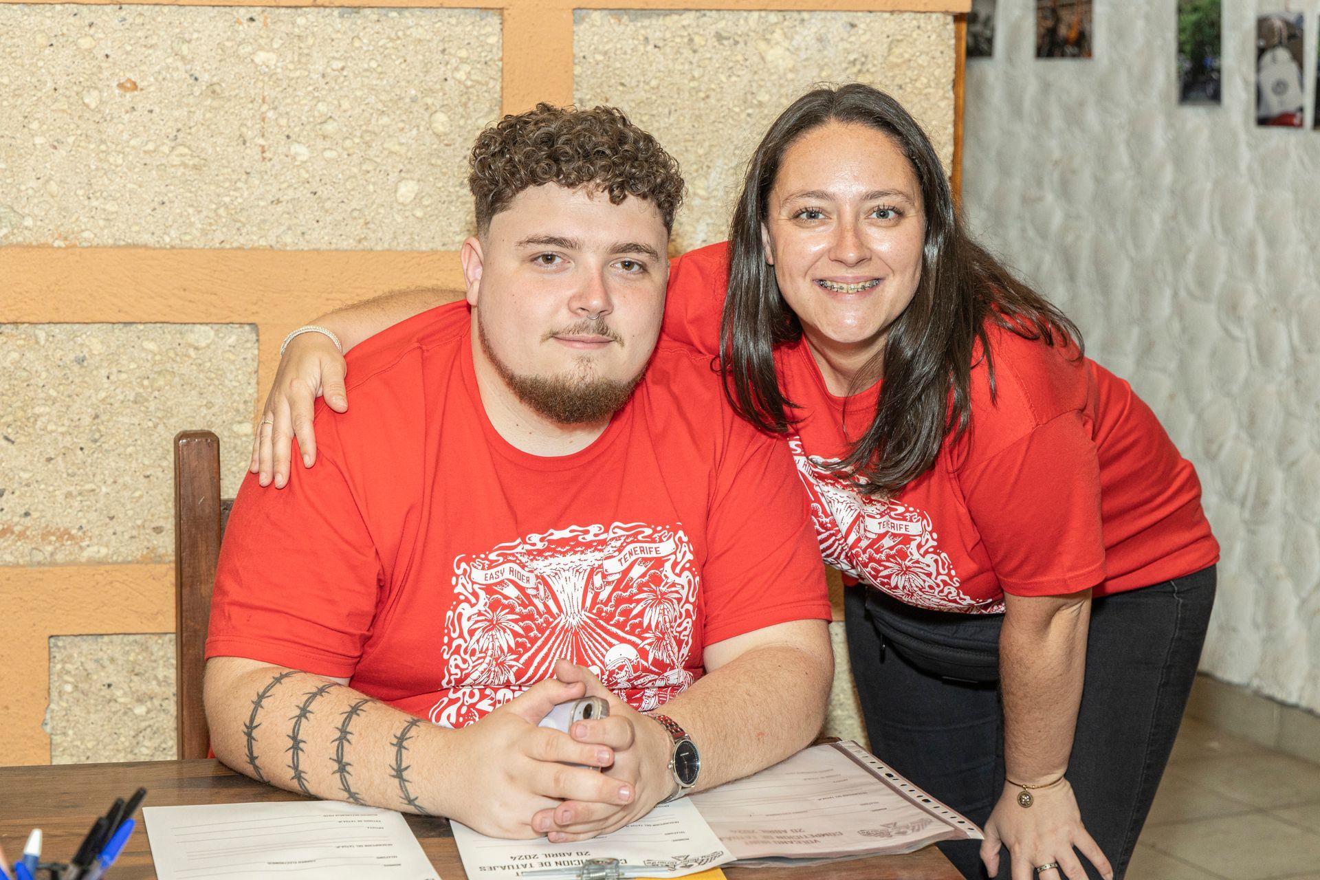 A man and a woman are posing for a picture while sitting at a table.
