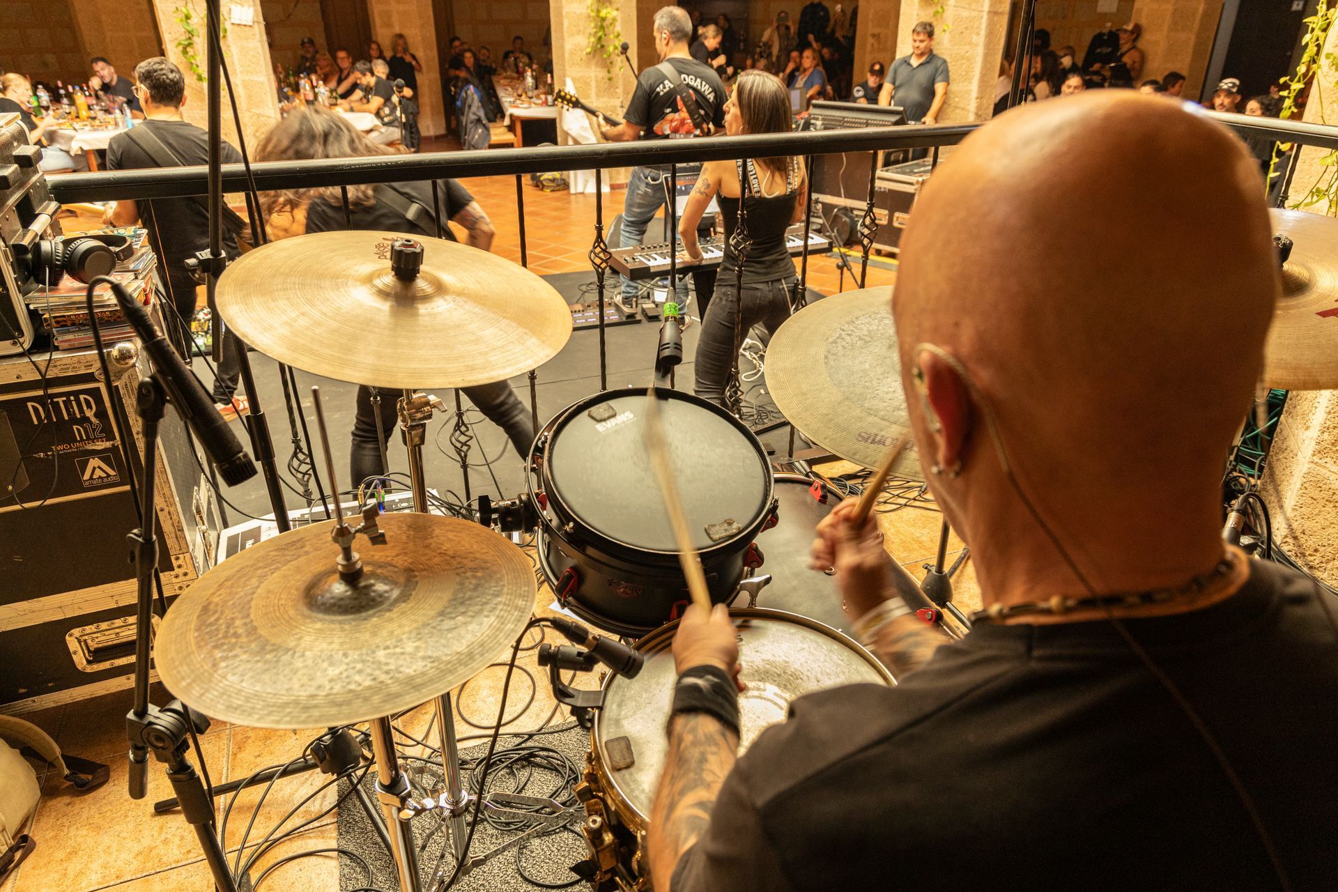 A bald man is playing drums on a stage in front of a crowd.