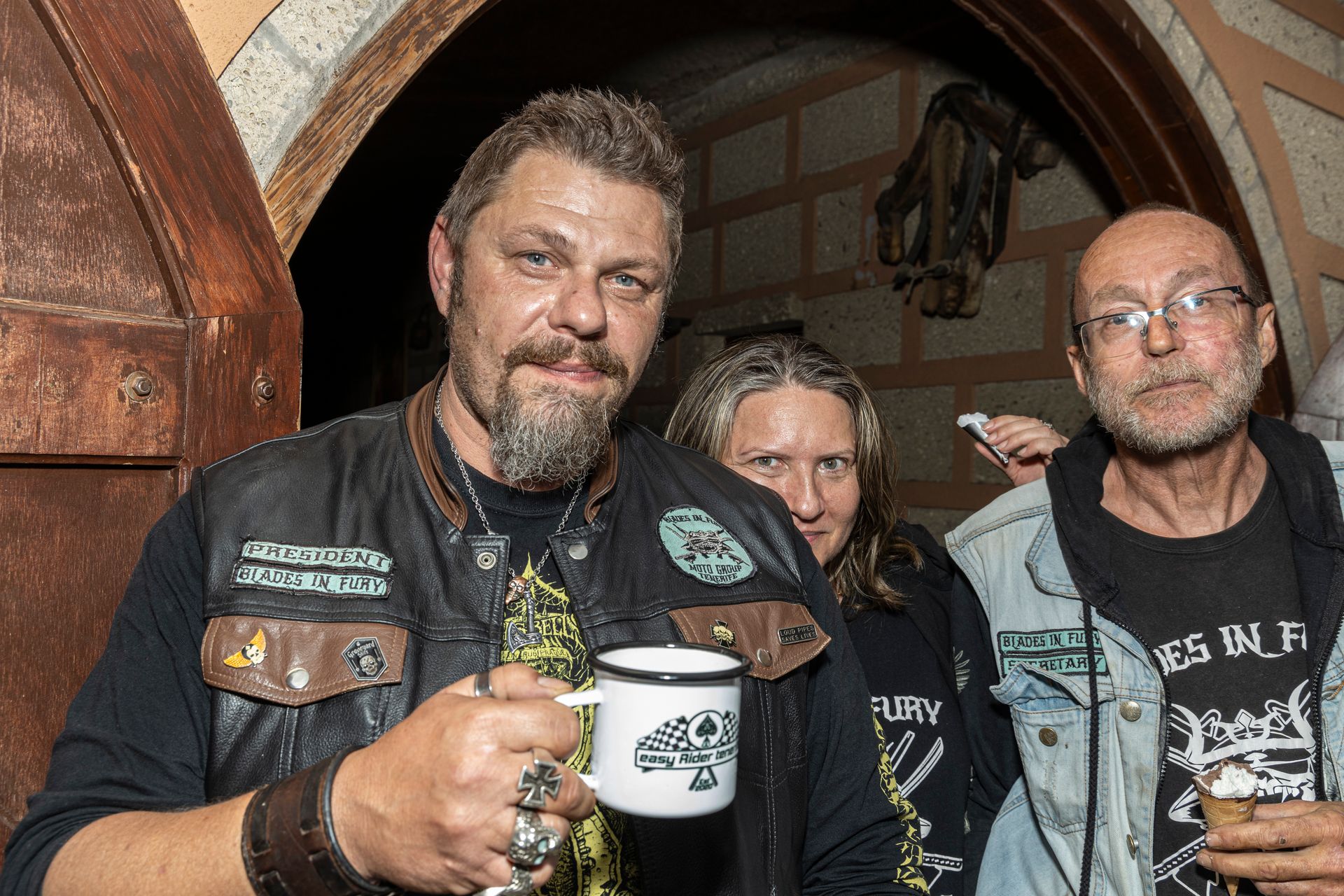 A group of people standing next to each other holding mugs of beer.