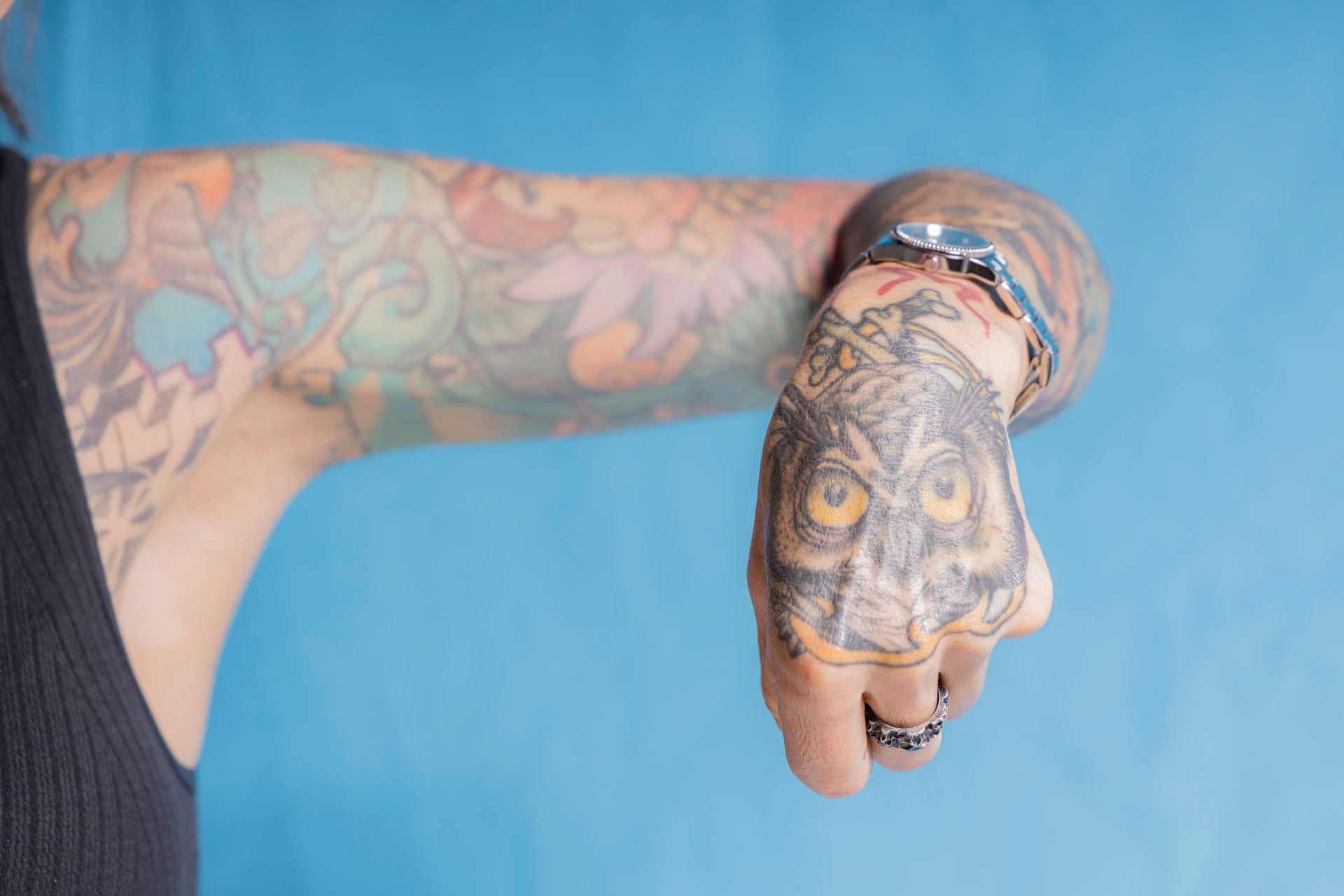 A woman with a tattoo on her hand is looking at her watch.