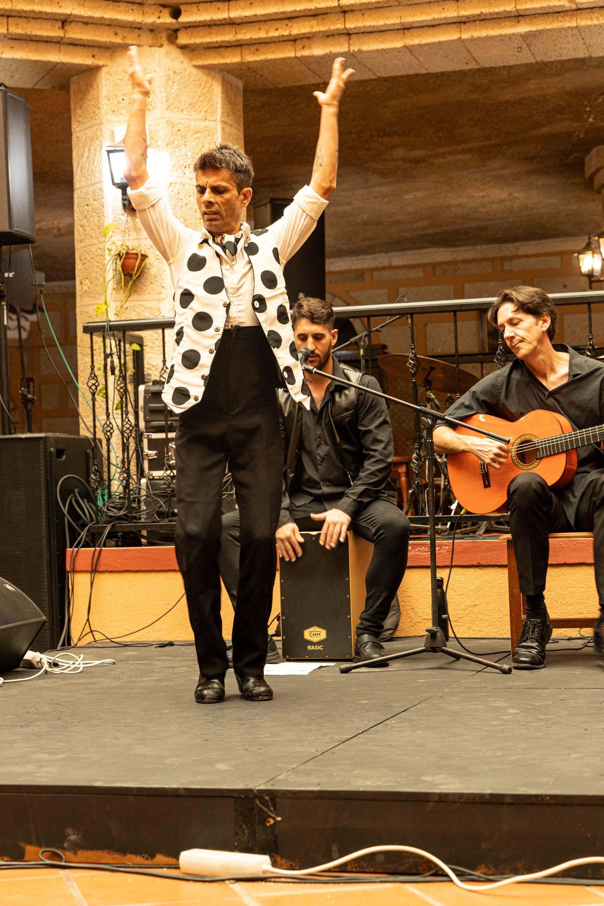 A man is dancing on a stage while two men play guitars