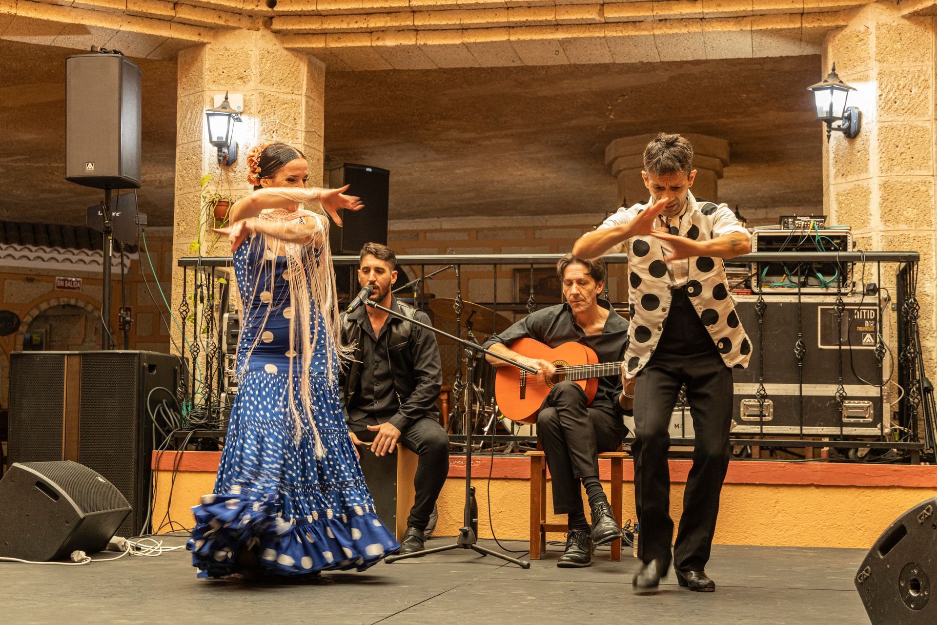 A man is playing a guitar and a woman is dancing in front of a group of people.