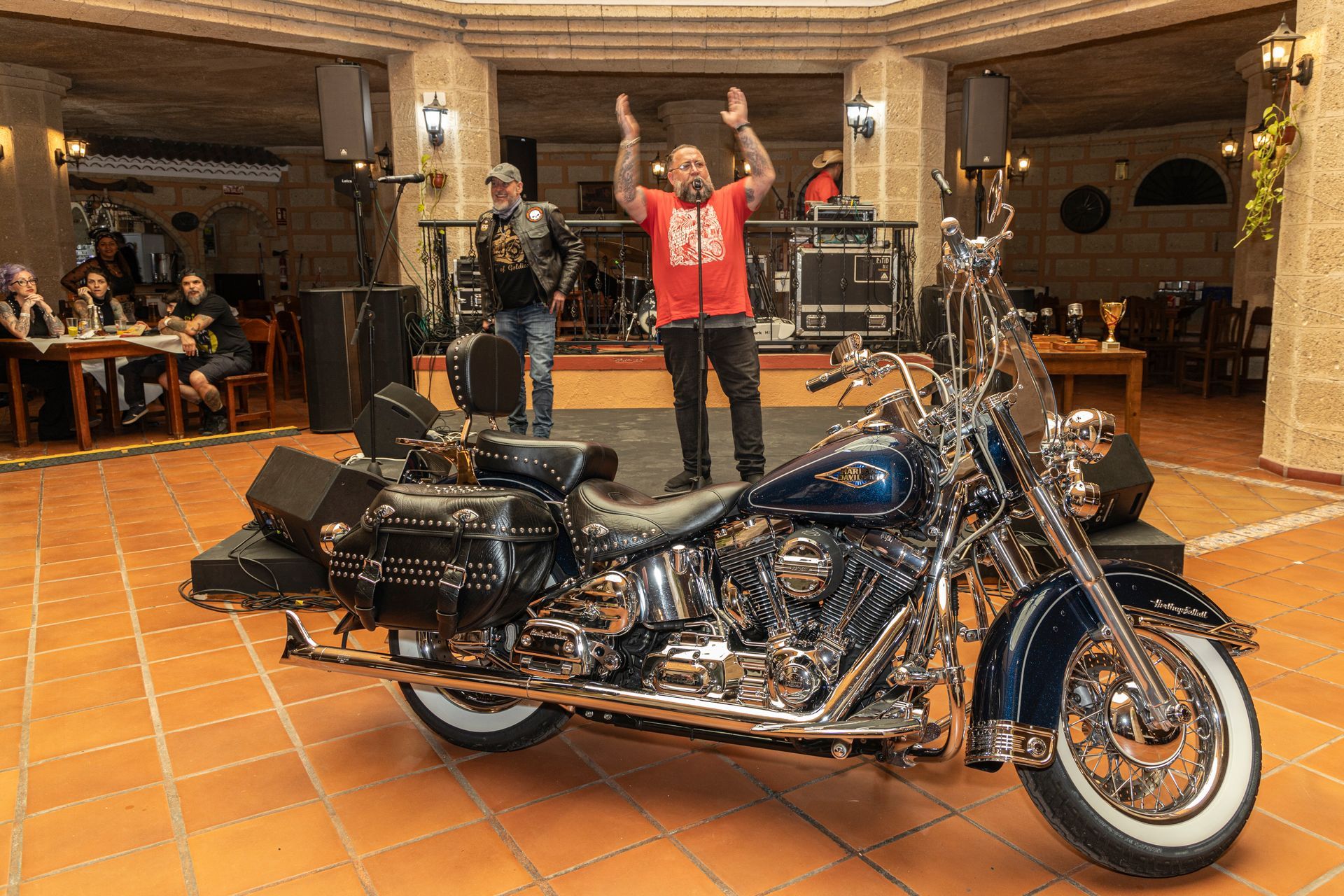 A man singing into a microphone next to a harley davidson motorcycle