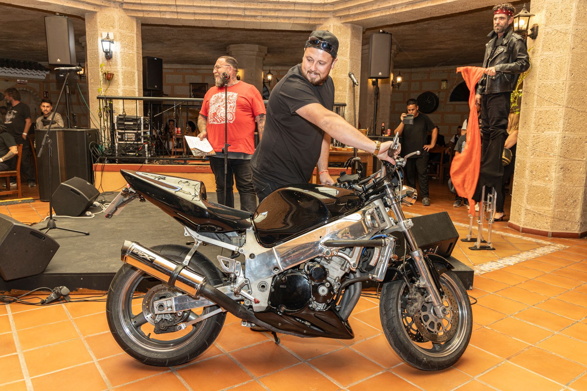 A man is standing next to a motorcycle in a room.