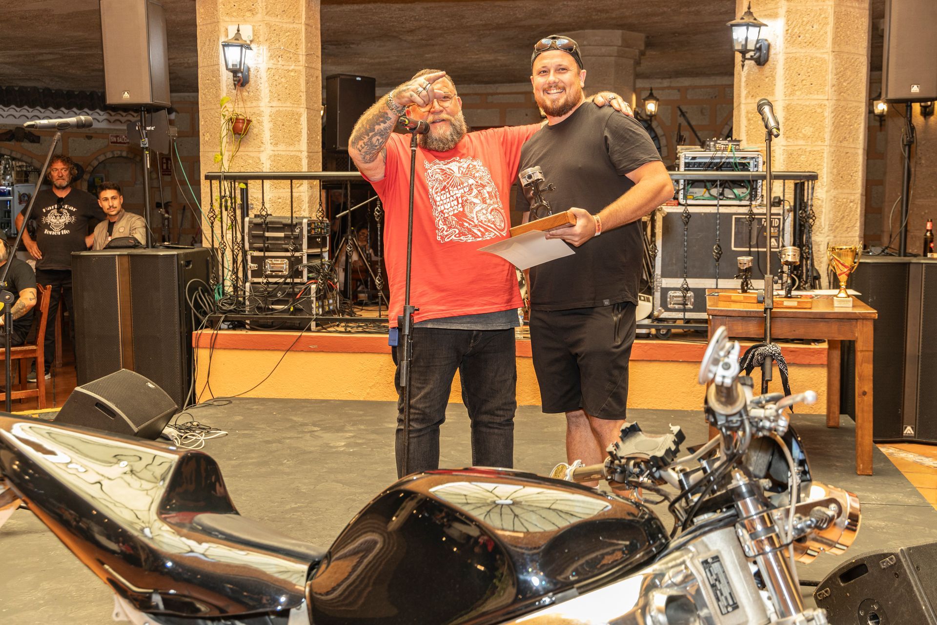 Two men standing next to a motorcycle holding a piece of paper