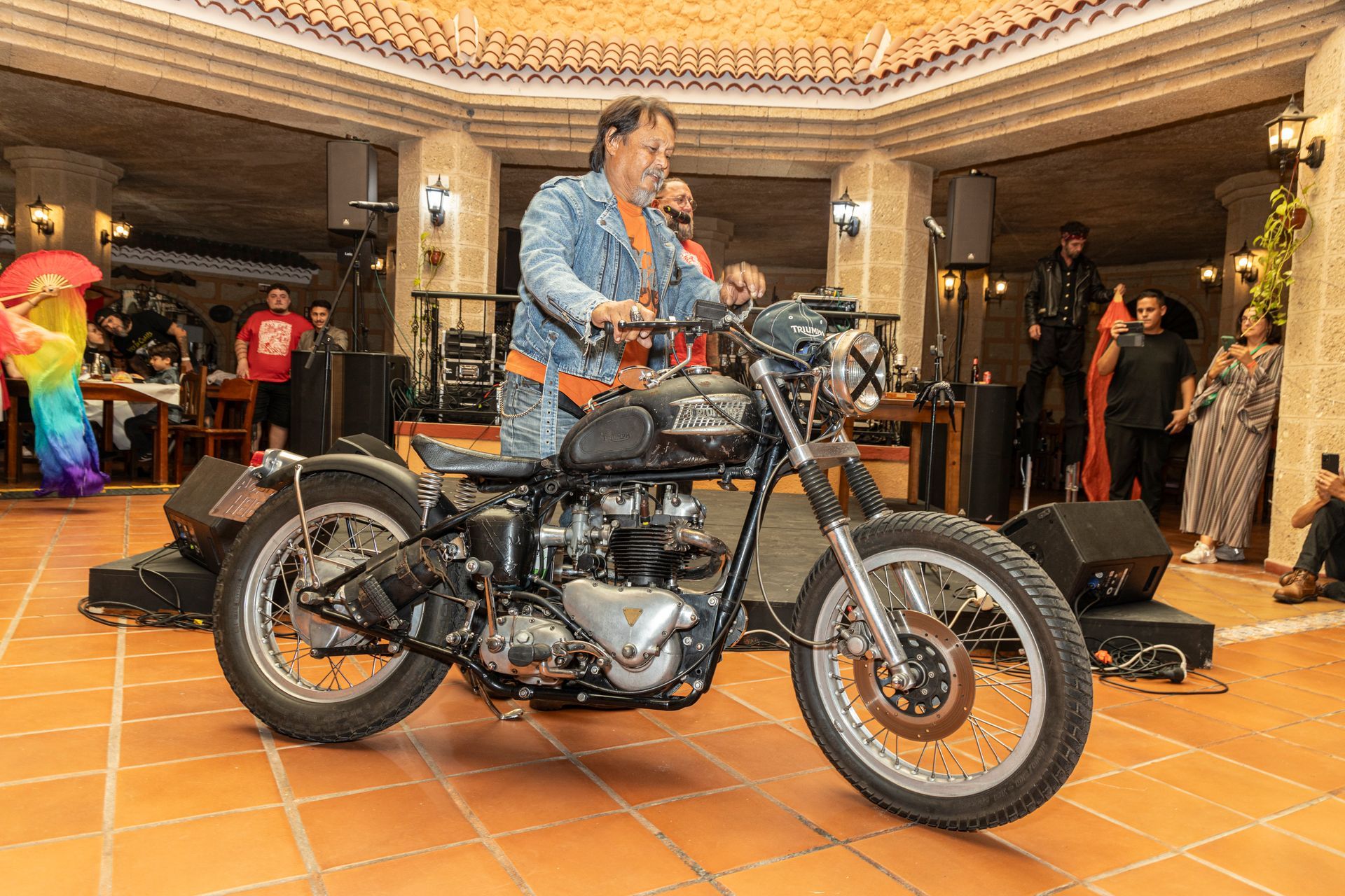 A man is riding a motorcycle on a tiled floor in a room.