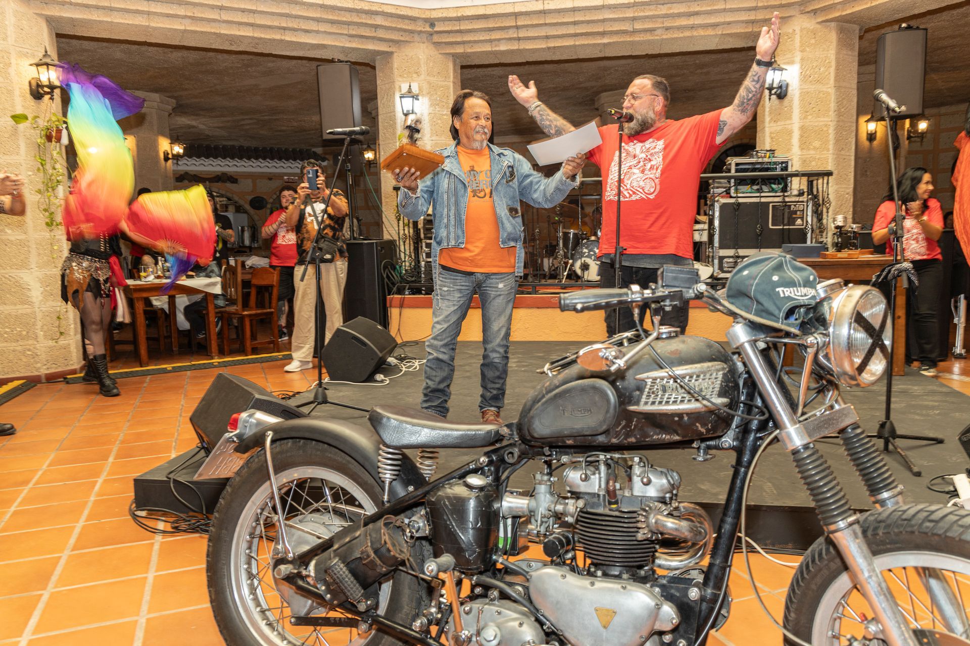 Two men are standing next to a motorcycle on a stage.