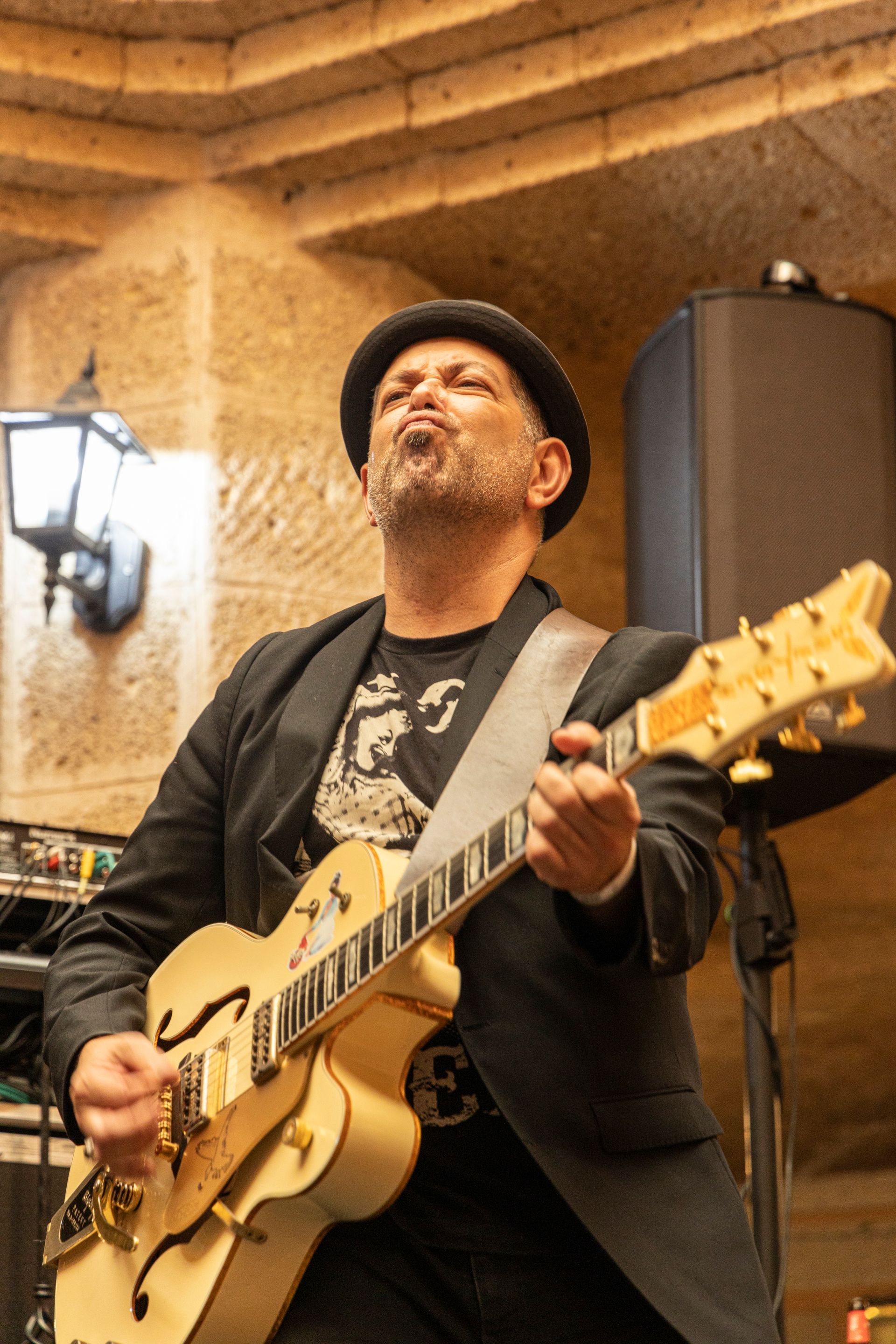 A man in a suit and hat is playing a guitar.