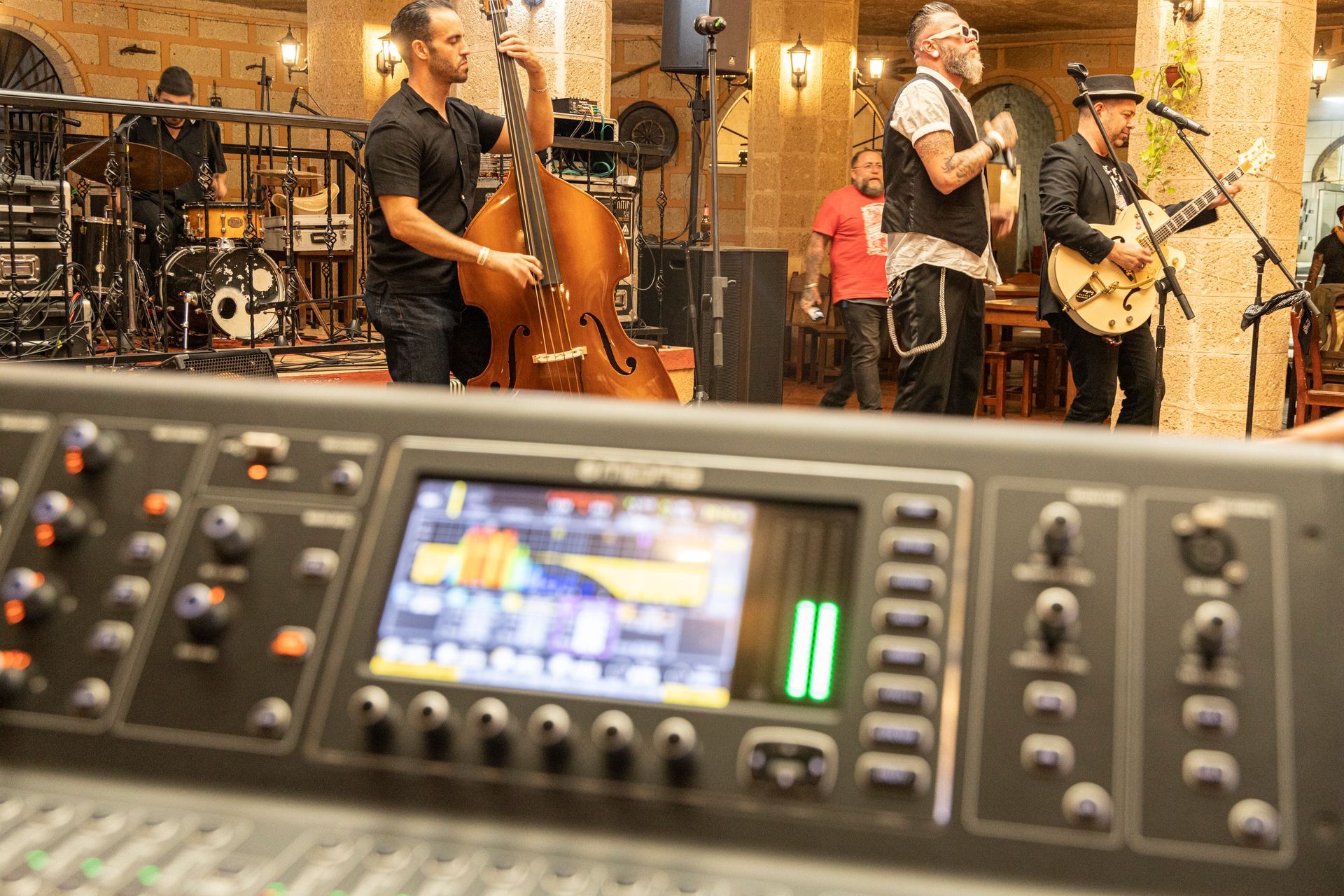 A group of men are playing instruments in front of a mixer.