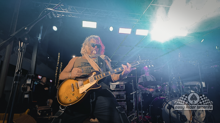 A man is playing a guitar on a stage in a dark room.