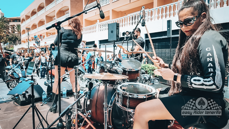 A woman is playing drums on a stage in front of a crowd.