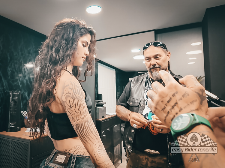 A man is talking to a woman with tattoos on her arm.