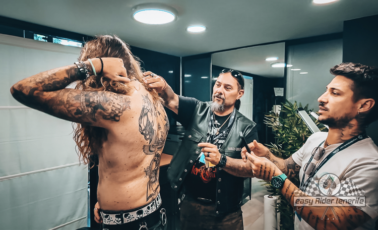 A man with tattoos on his back is getting ready for a concert.