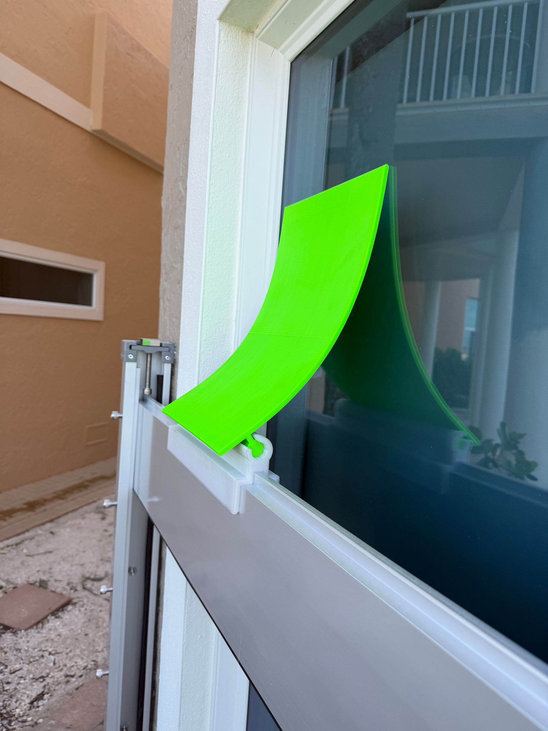 Green plastic window screen cover on a white window frame, outdoors.