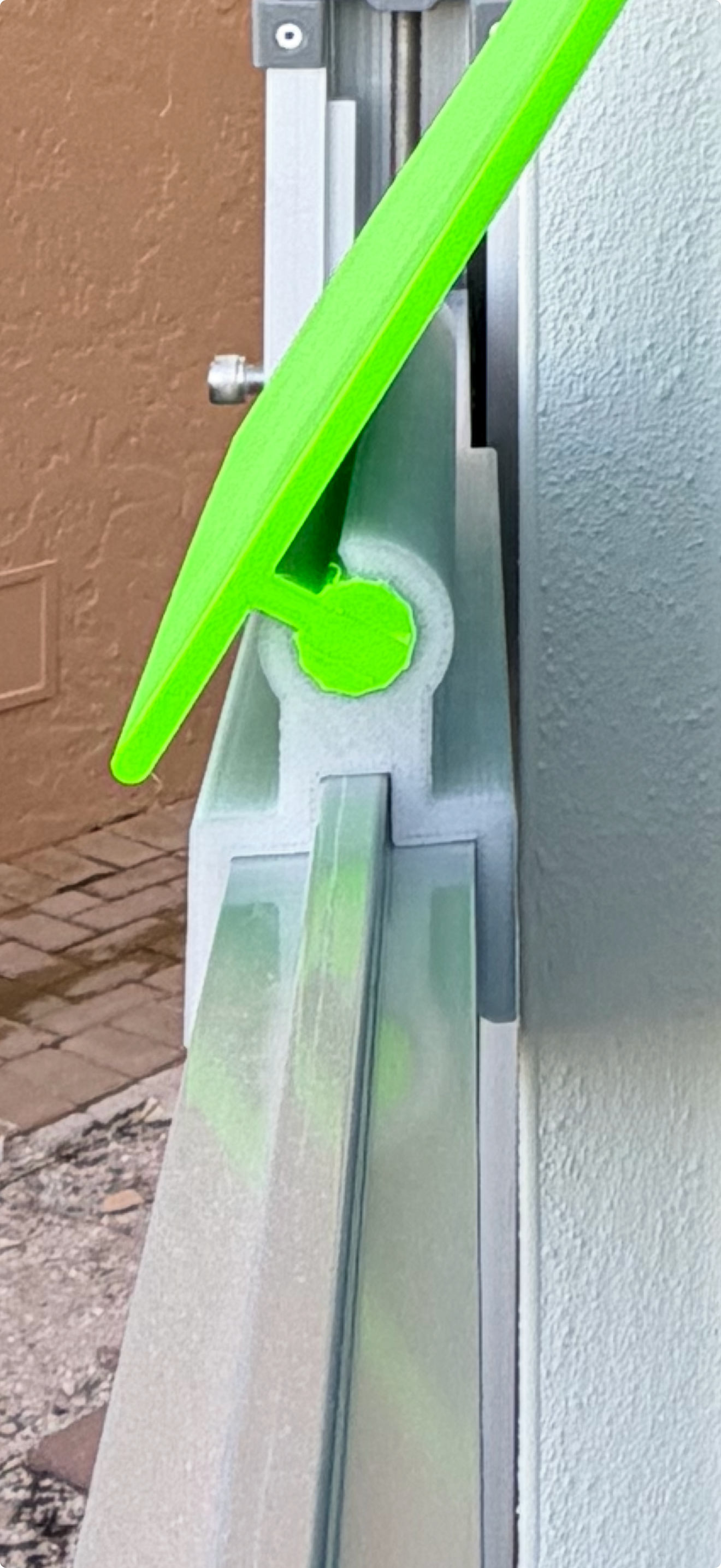 A green squeegee cleaning a track, likely for a sliding door or window.