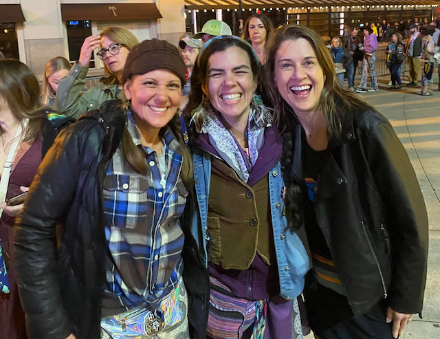 Three women are posing for a picture together and smiling.