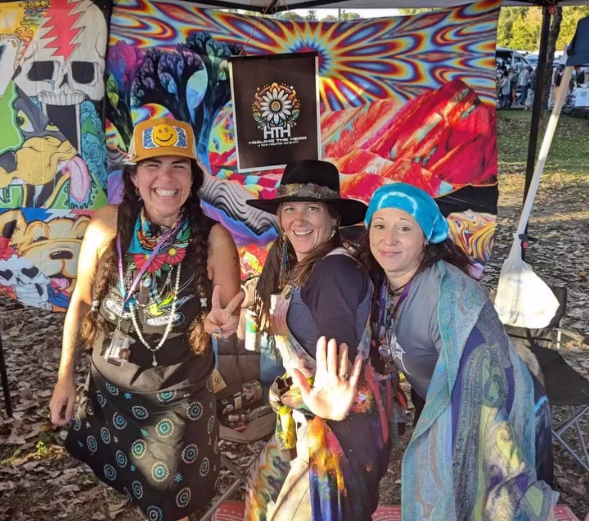 Three women are posing for a picture in front of a colorful wall.