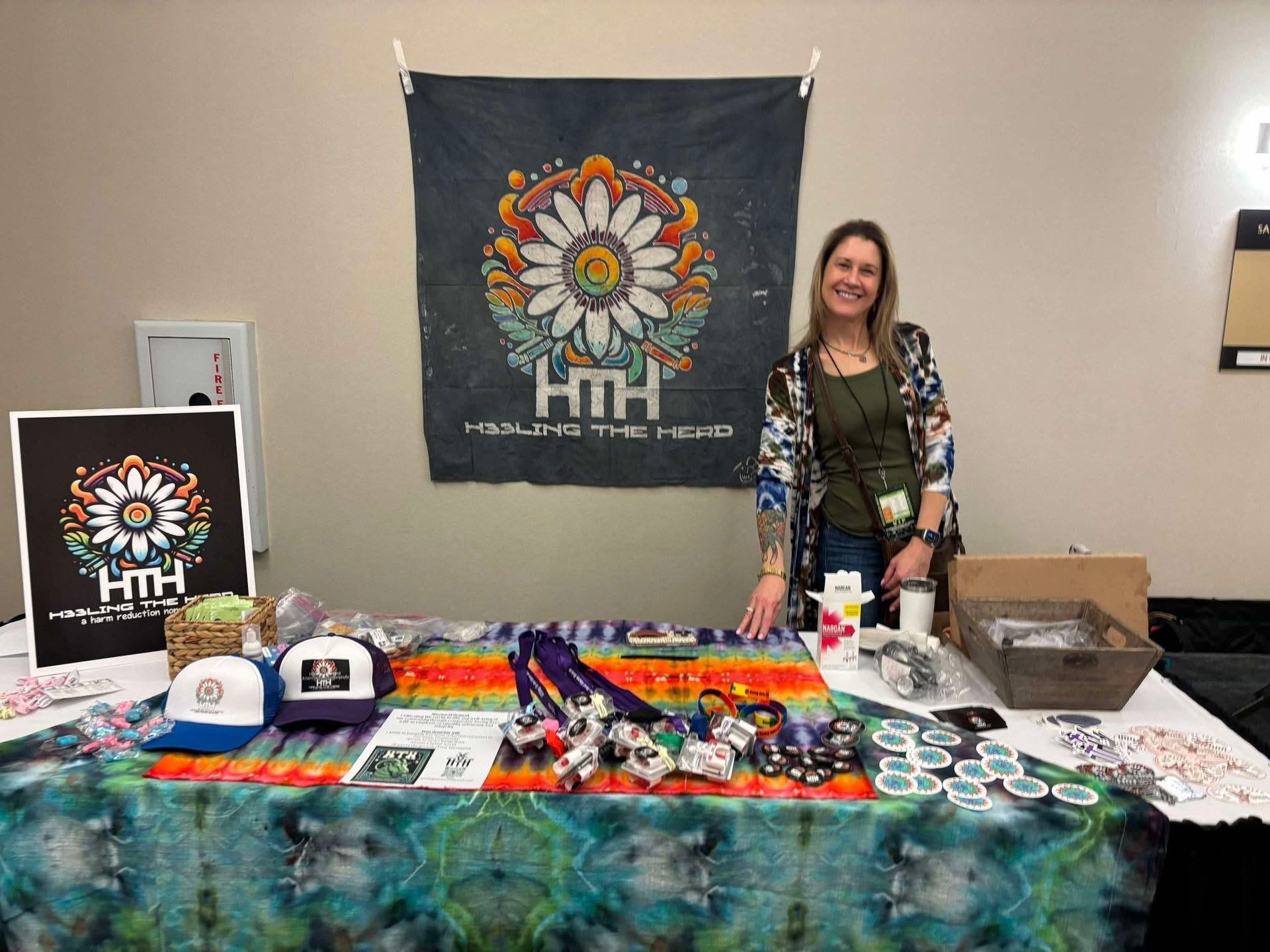 A woman is standing in front of a table filled with lots of items.