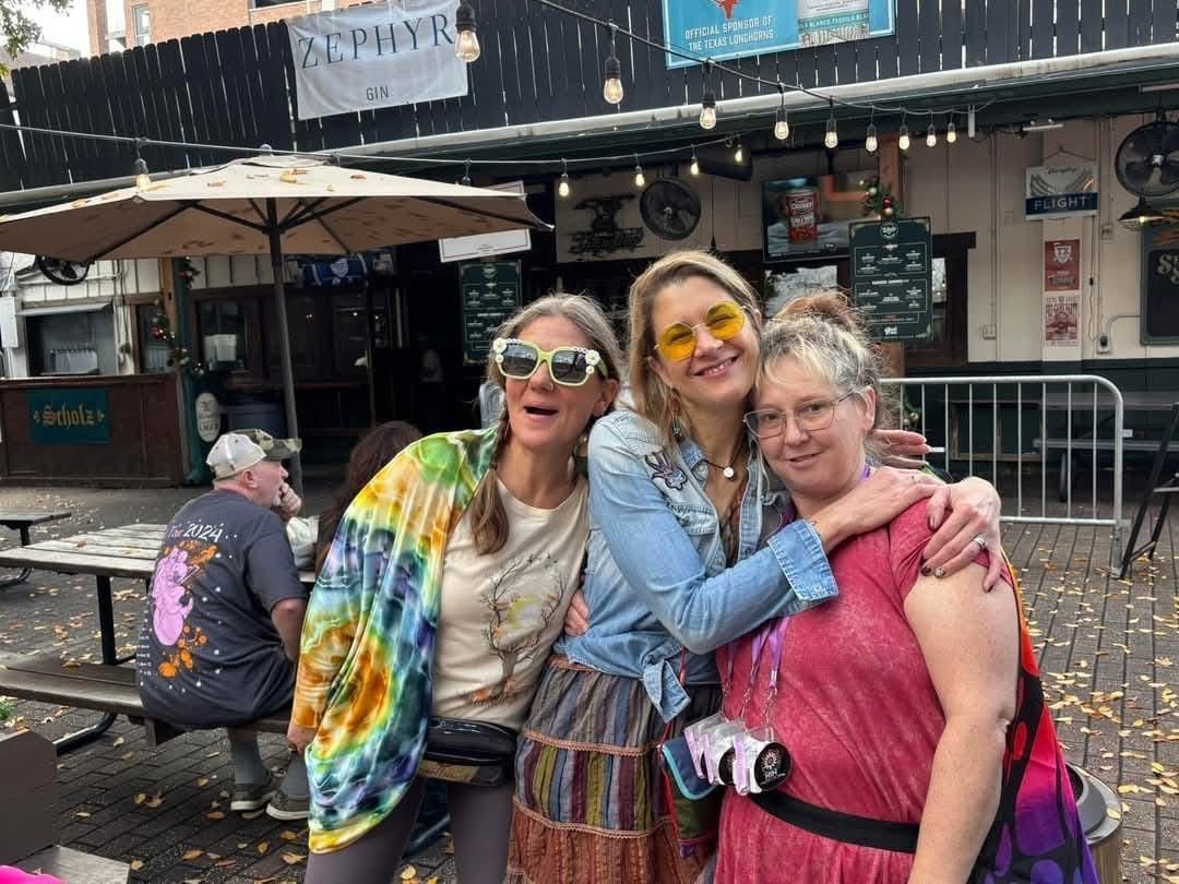 Three women are posing for a picture in front of a restaurant.